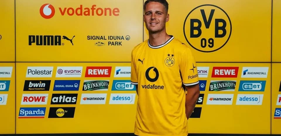 Jugador posando en conferencia de prensa con camiseta de Borussia Dortmund
