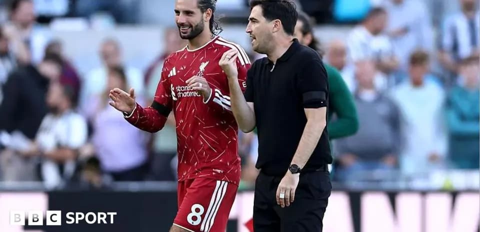 Jugador de Liverpool y entrenador conversando en el campo