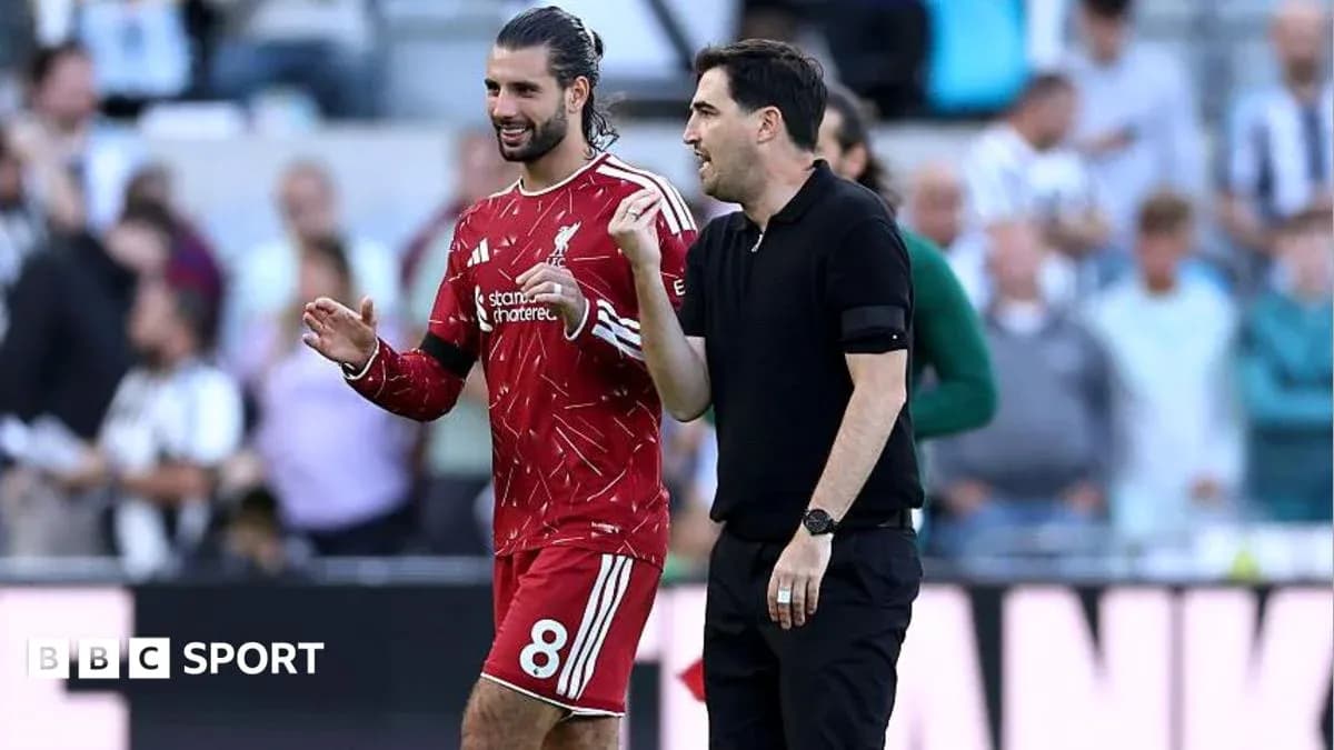 Jugador de Liverpool y entrenador conversando en el campo