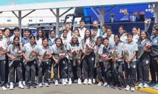 Equipo femenino posando con flores en el aeropuerto