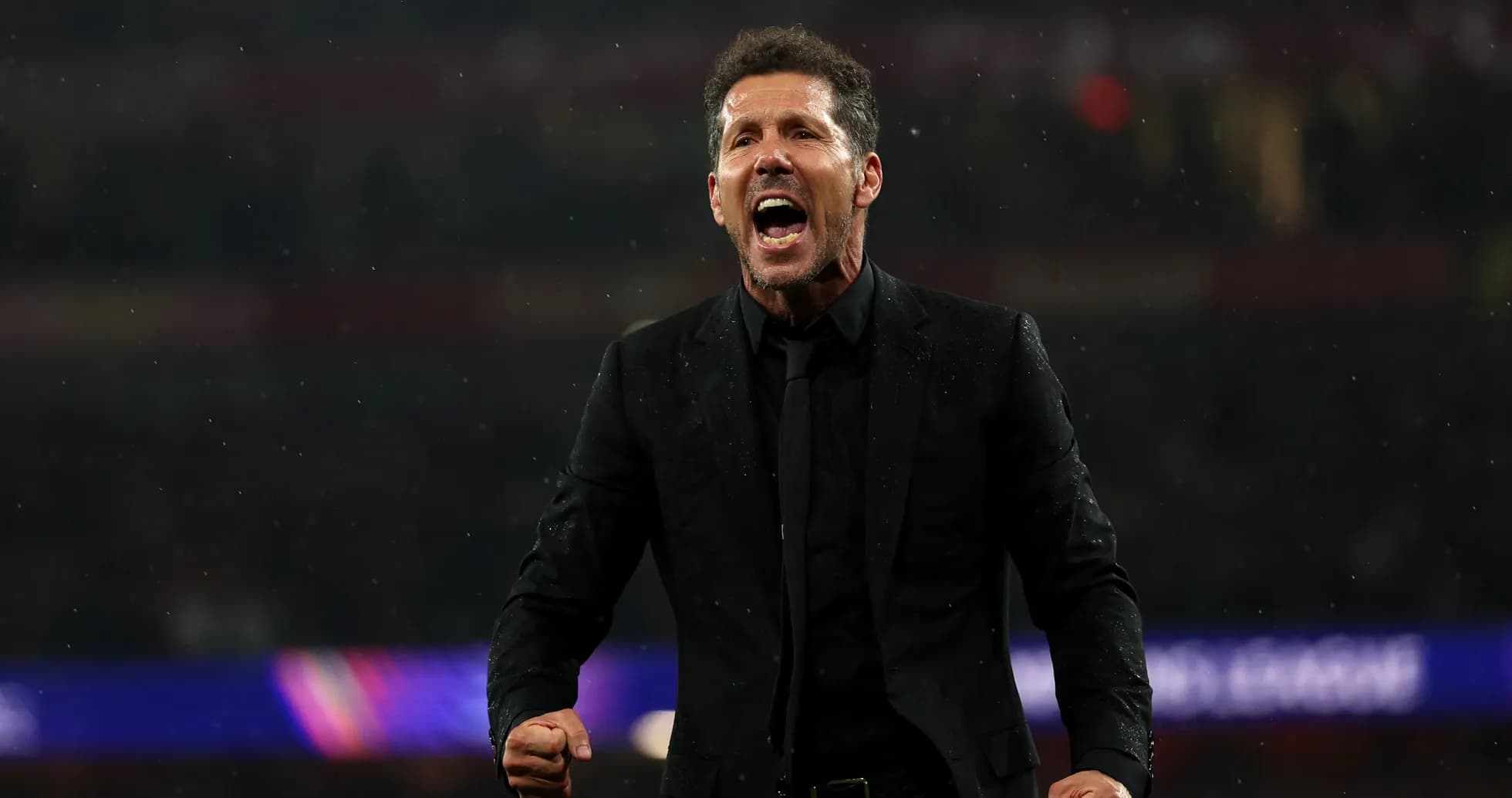 Entrenador celebrando durante un partido bajo la lluvia