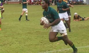 Jugador corriendo con balón durante partido de rugby
