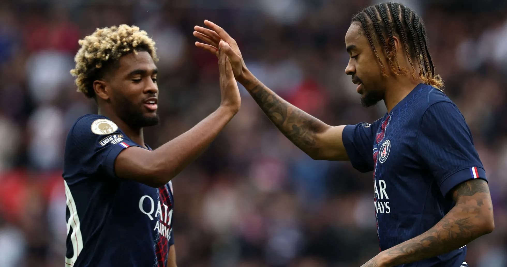 Dos jugadores de PSG chocando las manos en el campo