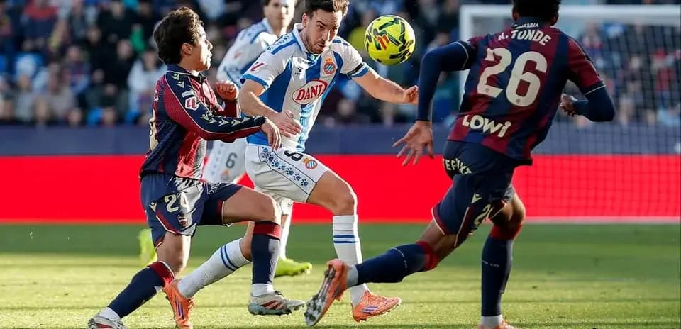 Jugador de Espanyol driblando a jugadores de Levante