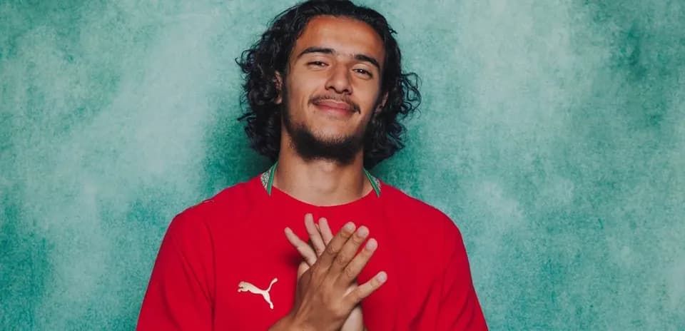 Jugador con camiseta roja sonriendo frente a fondo verde