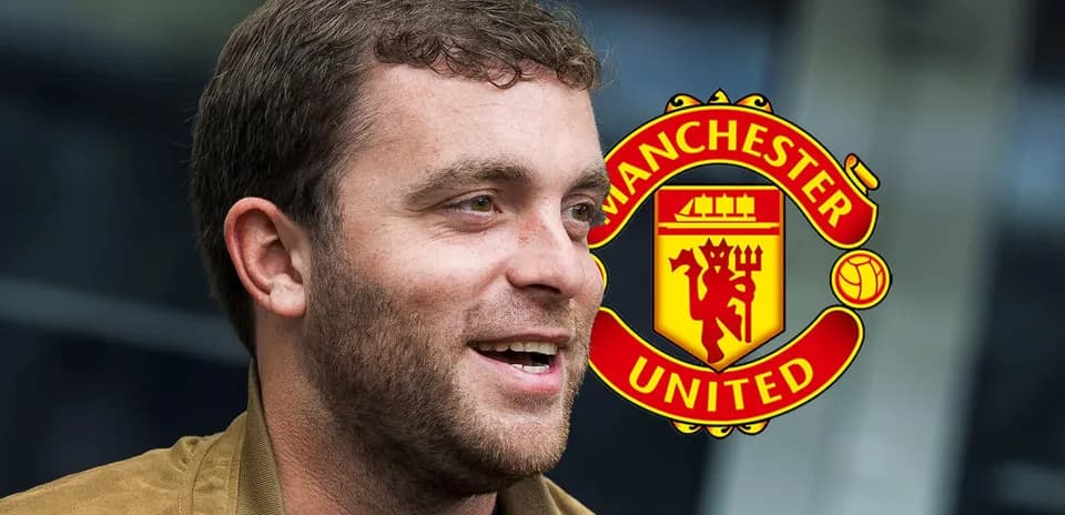 Hombre sonriendo frente al logo de Manchester United