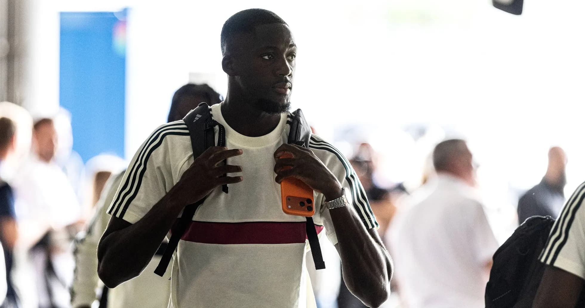 Jugador entrando con mochila y teléfono en mano