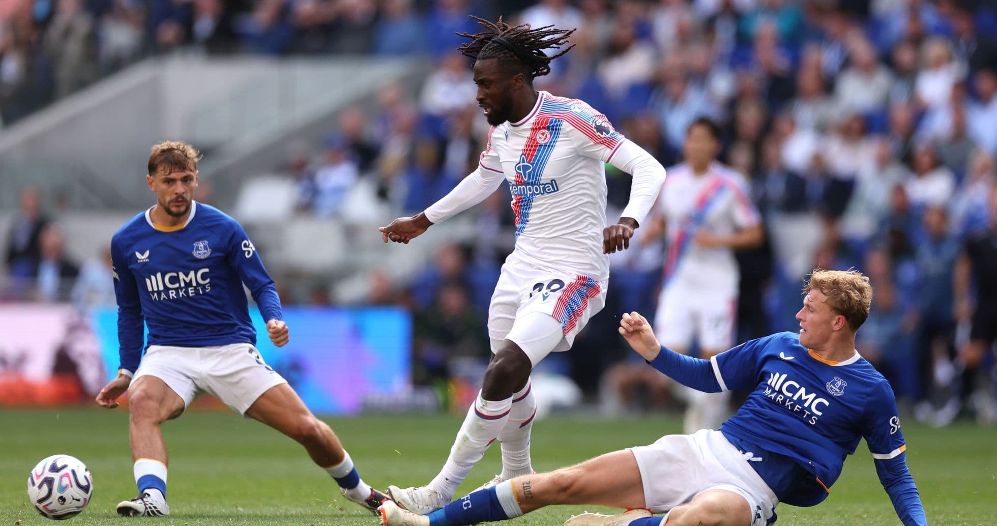 Jugador de Crystal Palace driblando entre dos rivales de Everton