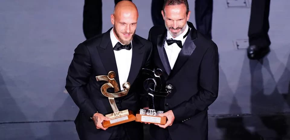 Dos hombres con trofeos en ceremonia de premiación
