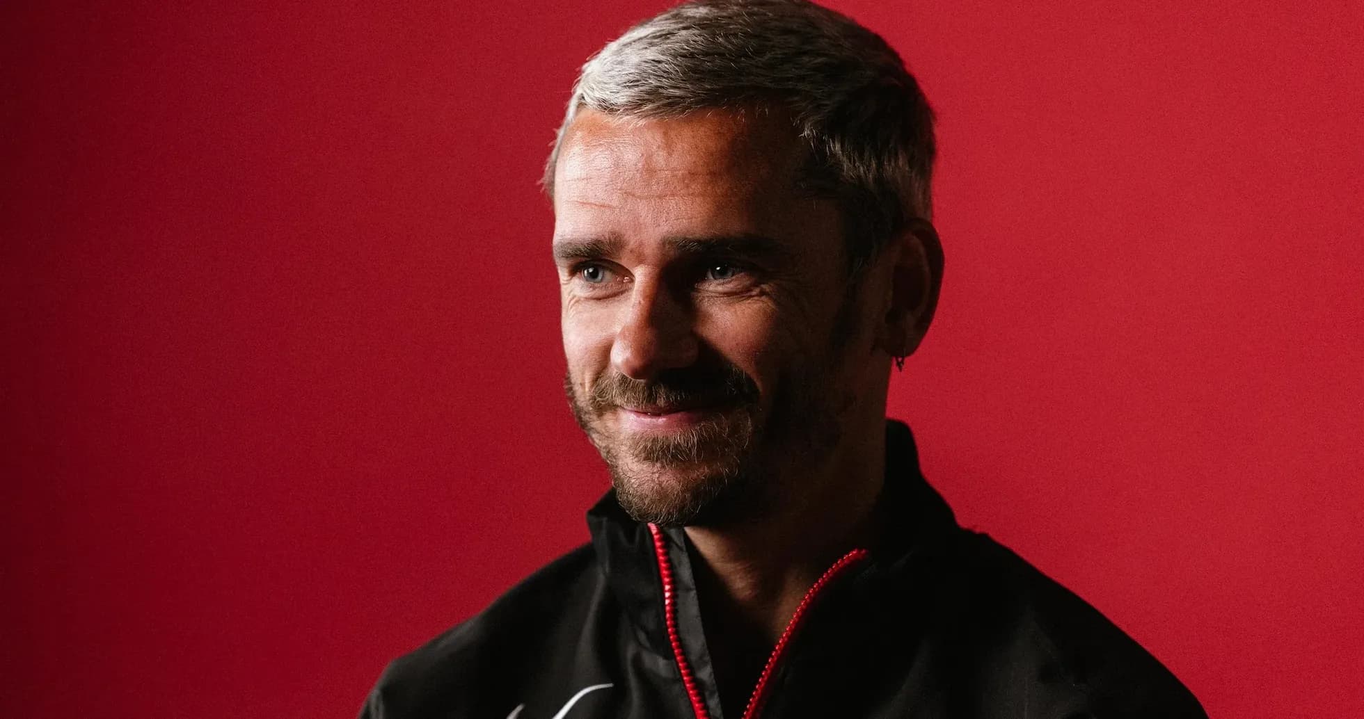 Entrenador sonriendo frente a fondo rojo