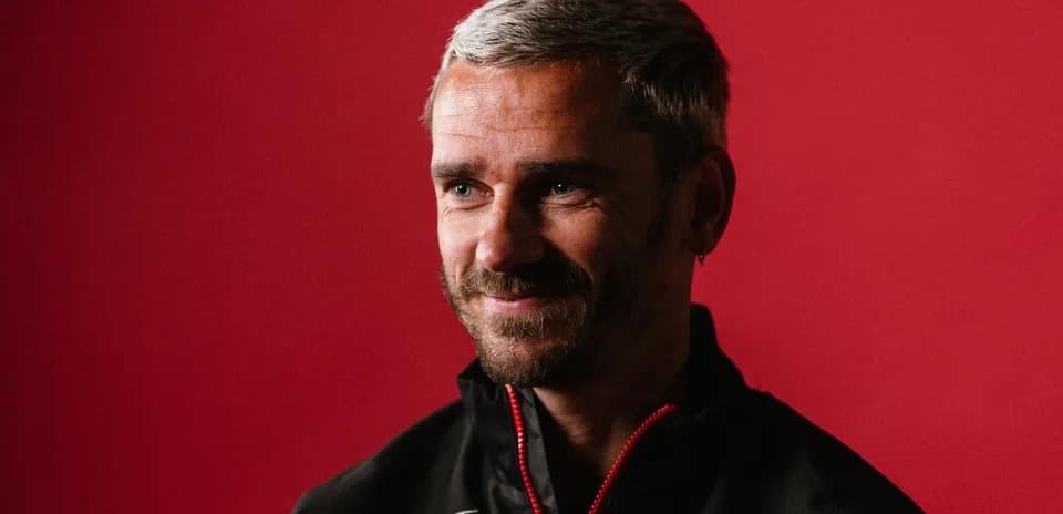 Entrenador sonriendo frente a fondo rojo