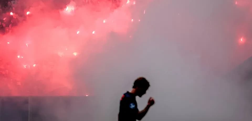 Jugador celebrando con humo de bengalas de fondo