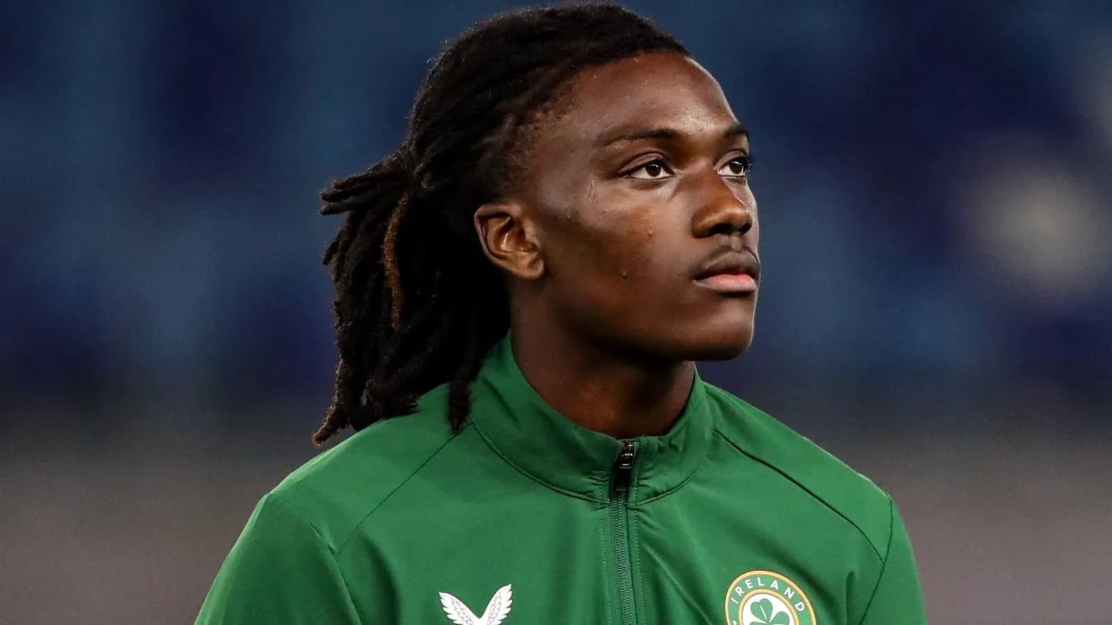 Jugador de fútbol con chaqueta verde mirando hacia arriba
