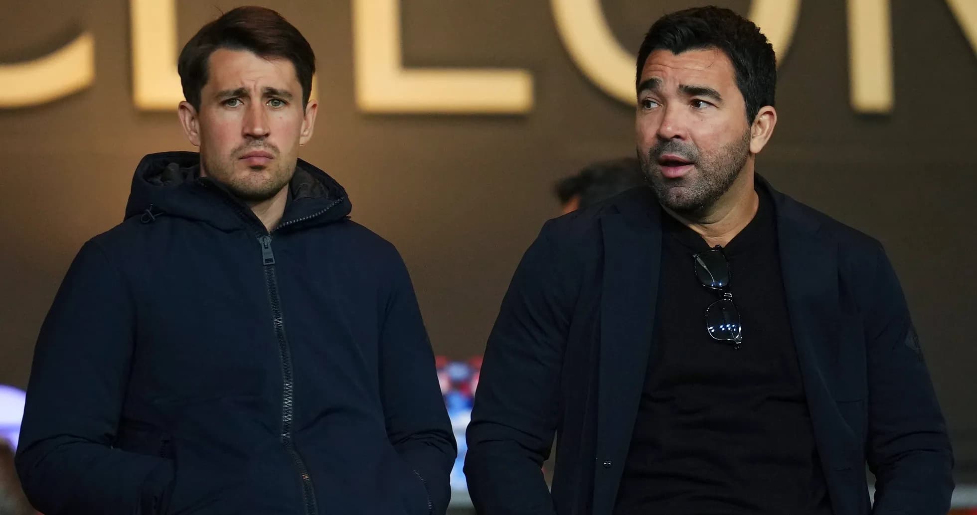 Dos hombres sentados en un palco de estadio