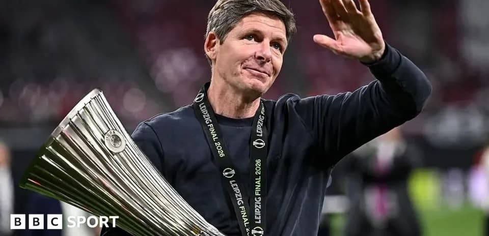 Entrenador sosteniendo trofeo y saludando tras la victoria