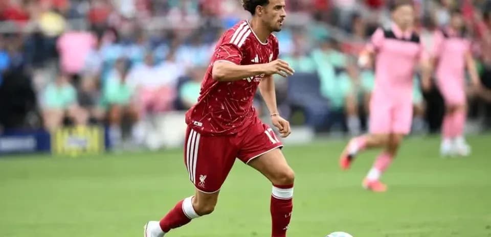Jugador de Liverpool corriendo con el balón en el campo