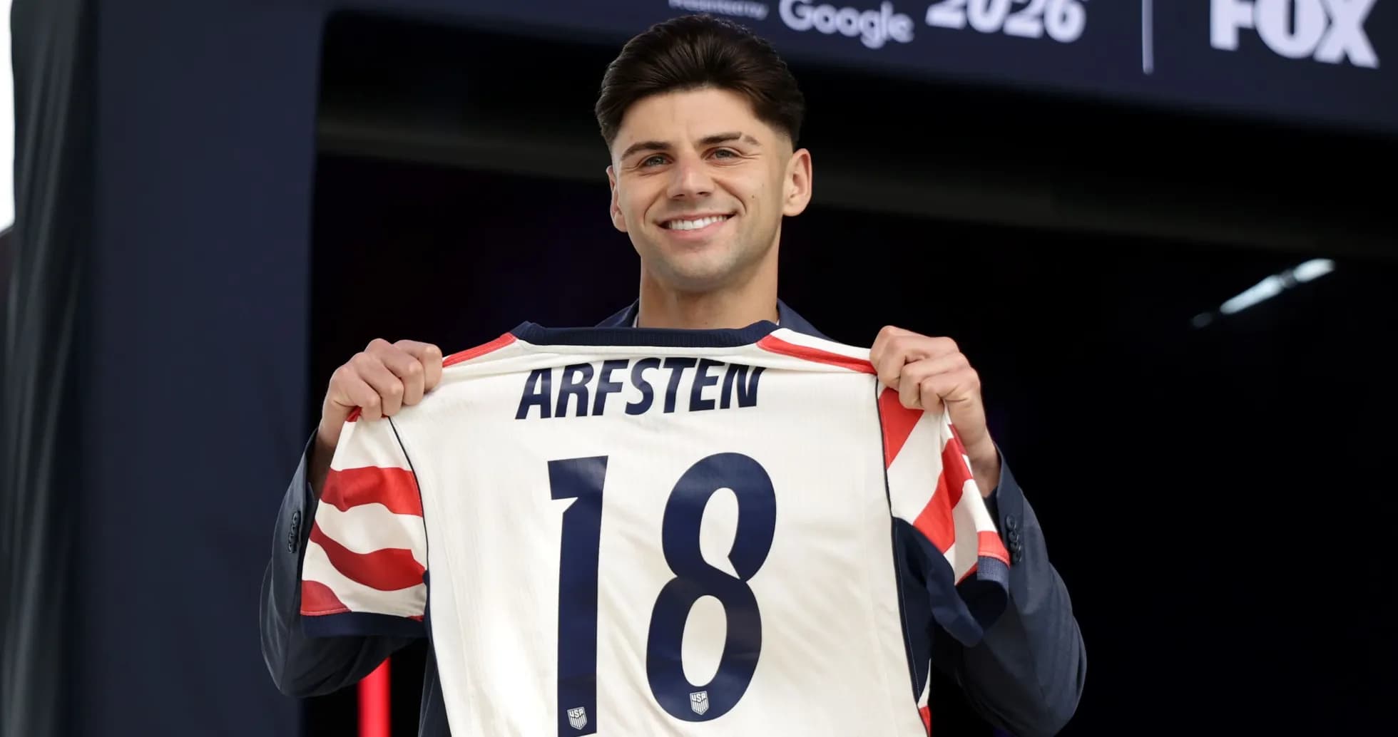 Jugador sosteniendo camiseta con nombre y número