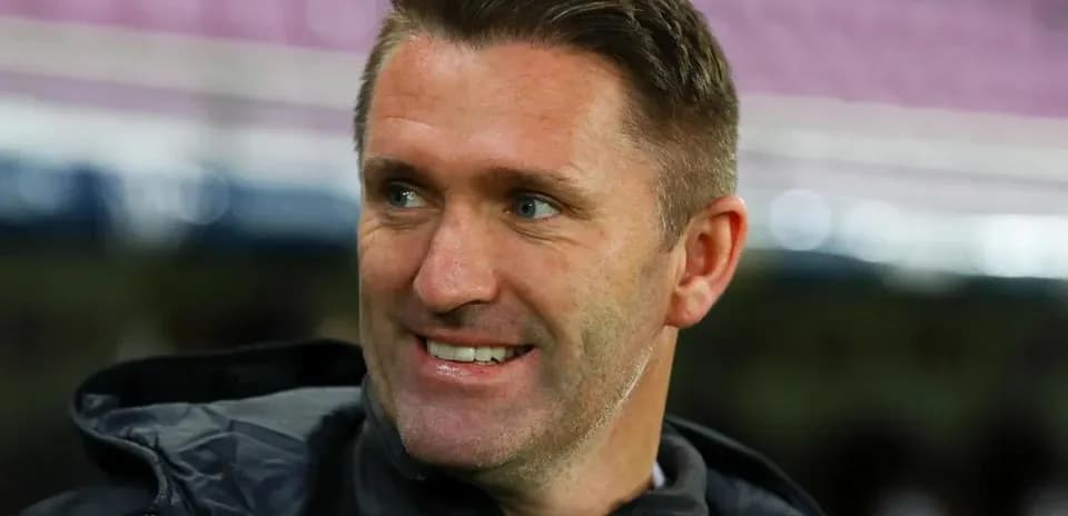 Entrenador sonriendo en el campo de fútbol