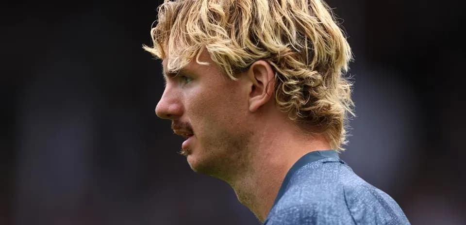 Jugador de perfil con cabello rizado y bigote
