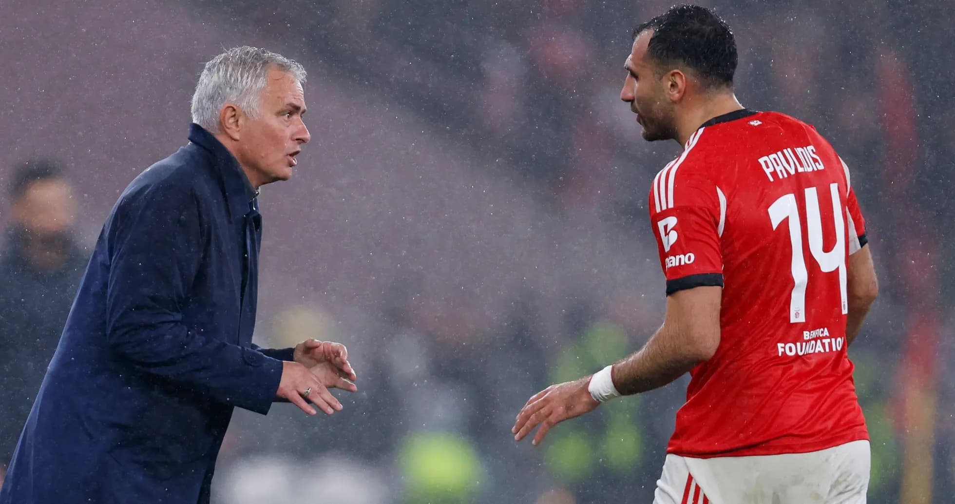 Entrenador hablando con jugador en lluvia durante partido