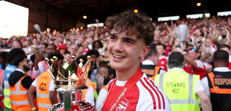 Jugador sosteniendo trofeo de la Premier League con aficionados