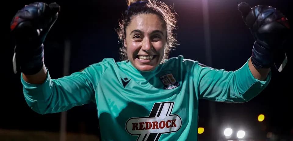 Portera celebrando con guantes en la noche