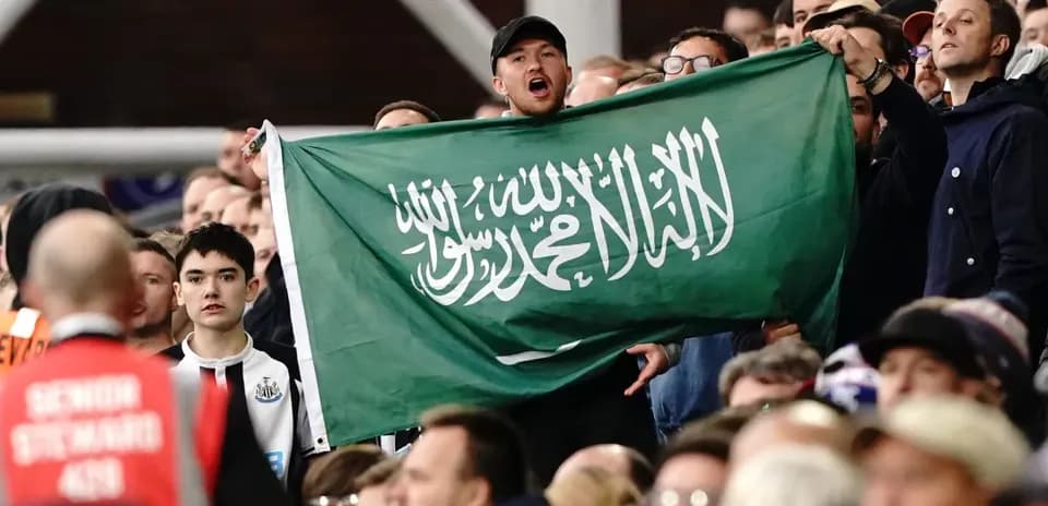 Afan de pie sosteniendo una bandera de Arabia Saudita