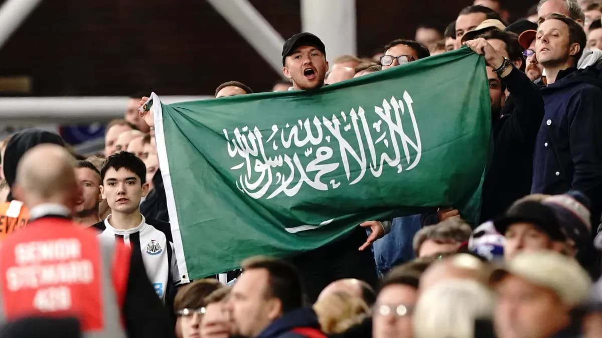 Afan de pie sosteniendo una bandera de Arabia Saudita