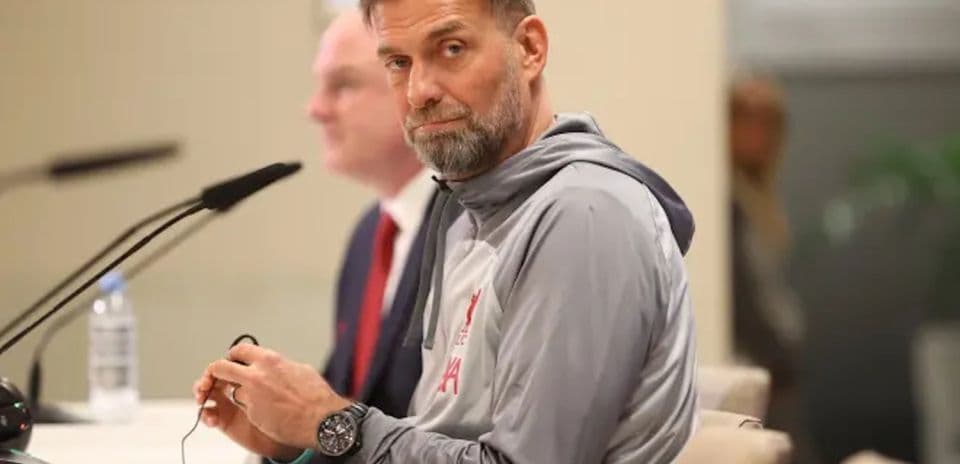 Entrenador en conferencia de prensa sentado en mesa