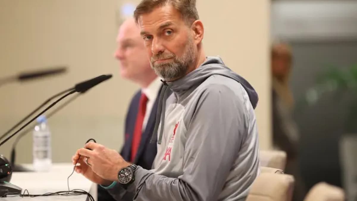 Entrenador en conferencia de prensa sentado en mesa