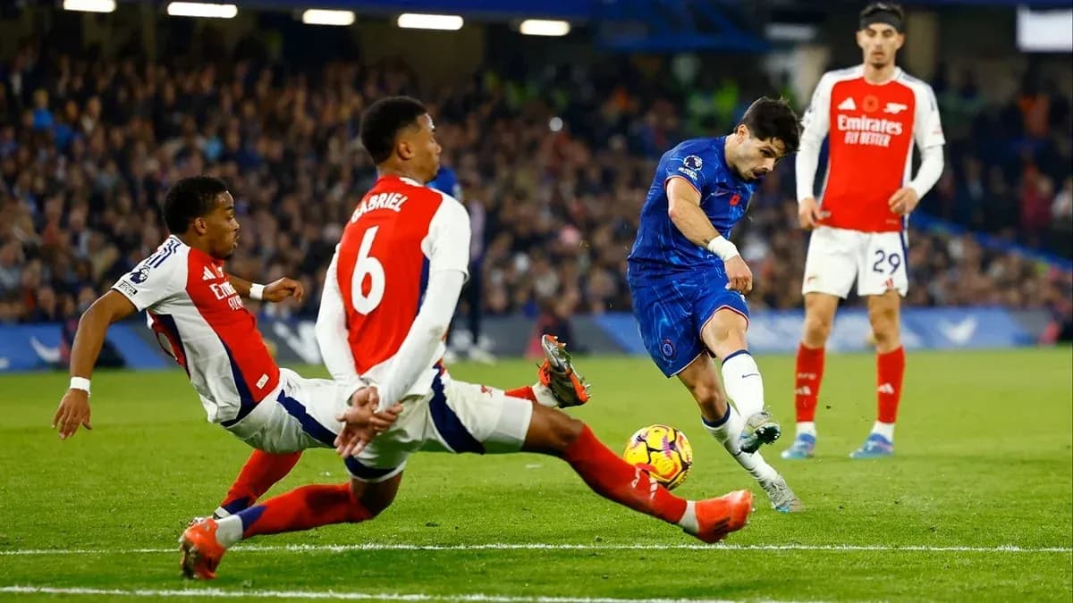 Jugador de Chelsea disparando mientras es tackleado por Arsenal Jugador de Chelsea disparando mientras es tackleado por Arsenal