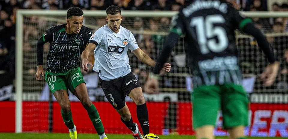 Dos jugadores compitiendo por el balón en La Liga Dos jugadores compitiendo por el balón en La Liga