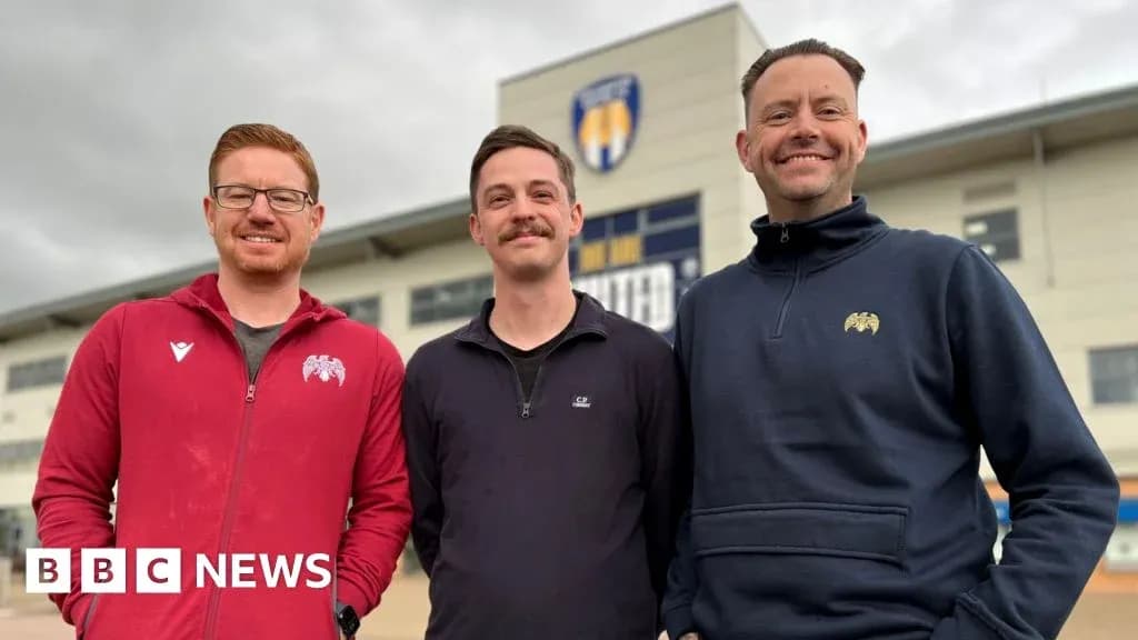 Tres hombres posando frente a un estadio Tres hombres posando frente a un estadio