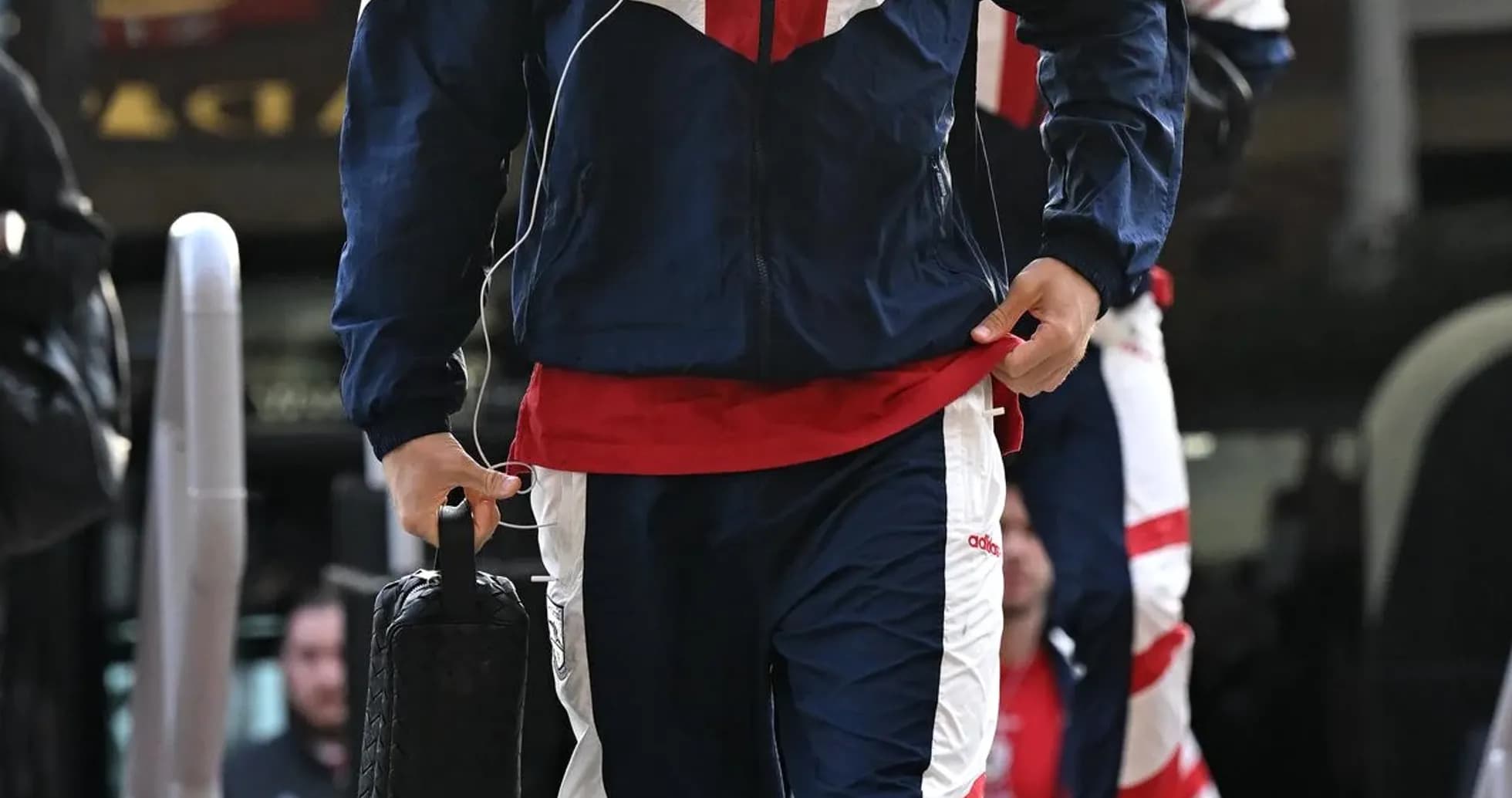 Jugador llegando con ropa de entrenamiento y auriculares Jugador llegando con ropa de entrenamiento y auriculares