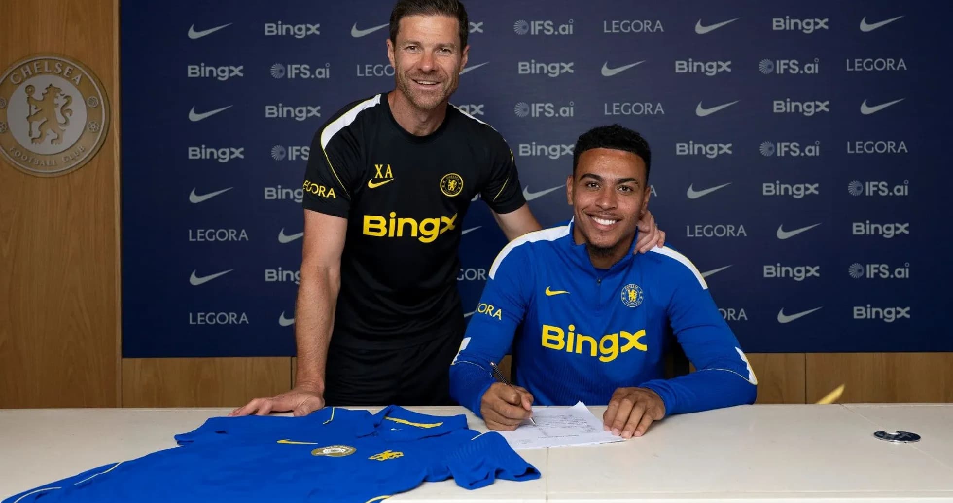 Jugador firmando contrato con entrenador en Chelsea Jugador firmando contrato con entrenador en Chelsea
