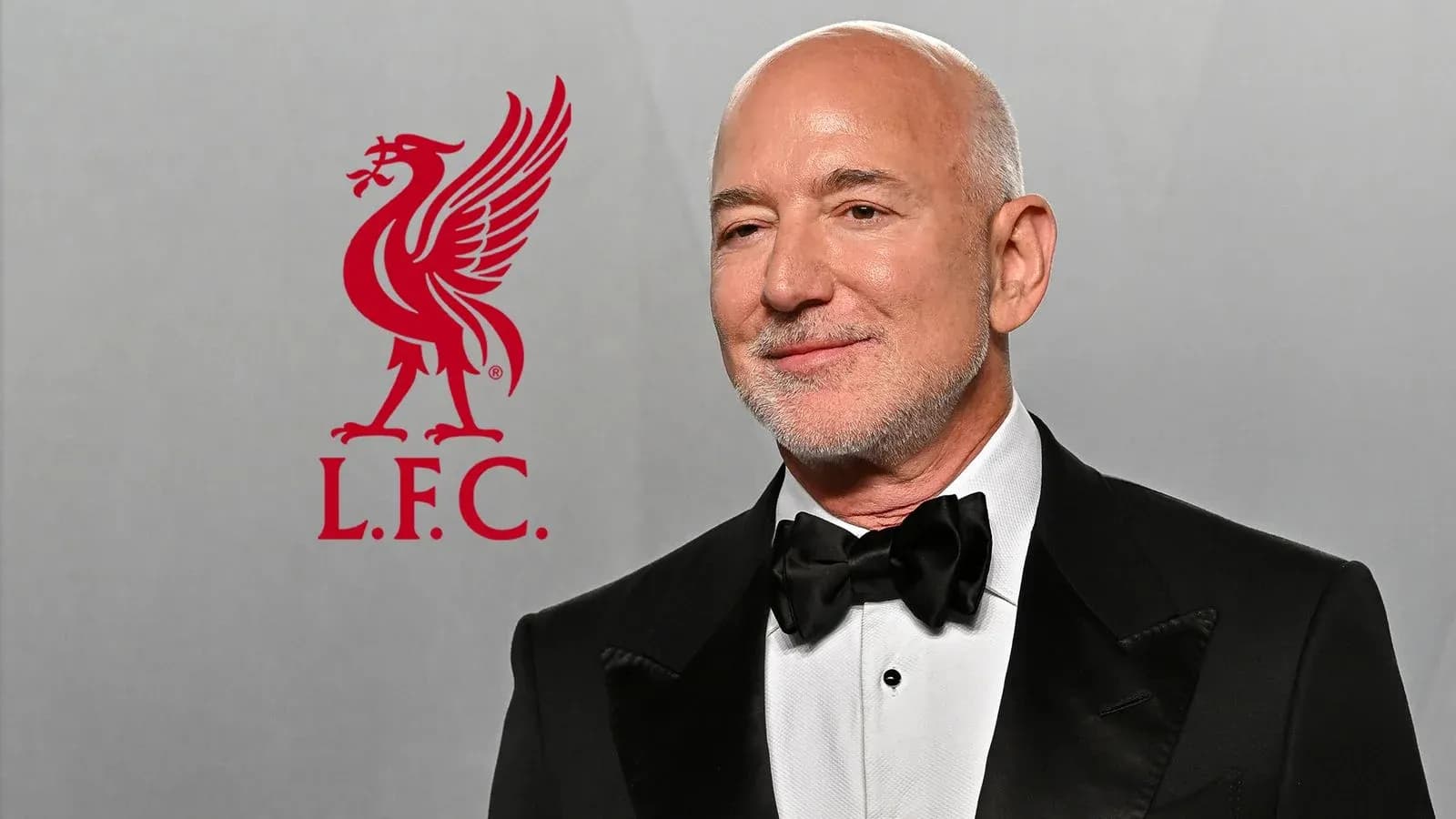 Hombre con traje en evento, logo de Liverpool F.C. detrás Hombre con traje en evento, logo de Liverpool F.C. detrás