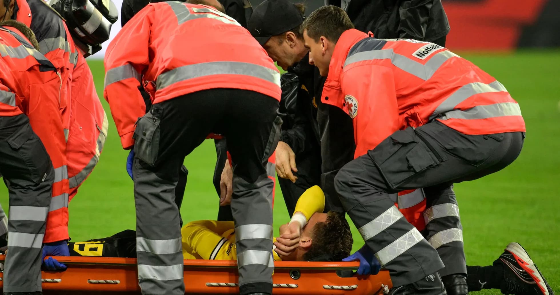 Equipo médico atendiendo a jugador lesionado en el campo Equipo médico atendiendo a jugador lesionado en el campo
