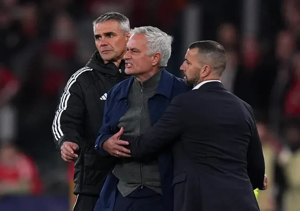 Entrenador siendo contenido por dos asistentes durante partido Entrenador siendo contenido por dos asistentes durante partido
