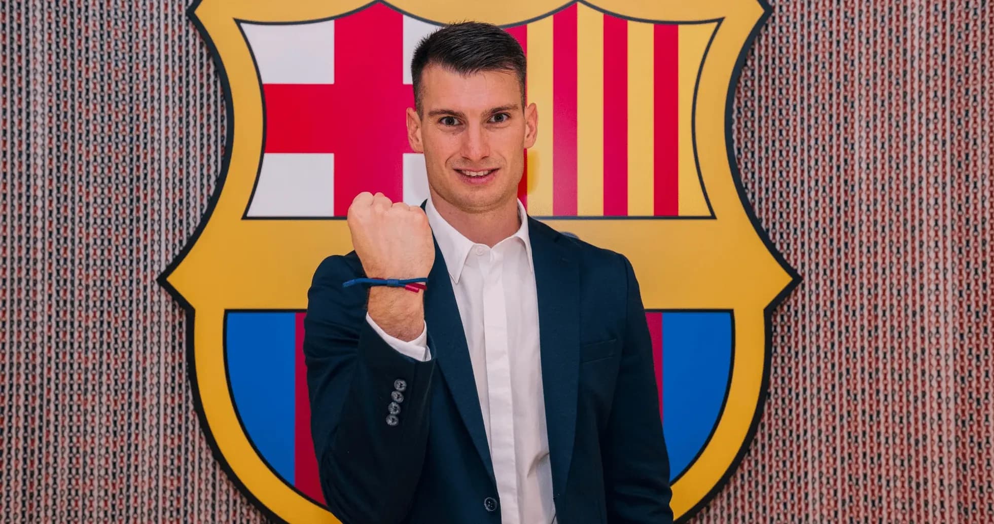 Jugador mostrando puño frente al escudo del Barcelona Jugador mostrando puño frente al escudo del Barcelona