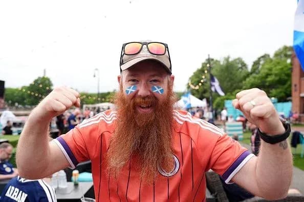 A fan celebrating with a Scottish flag face paint A fan celebrating with a Scottish flag face paint