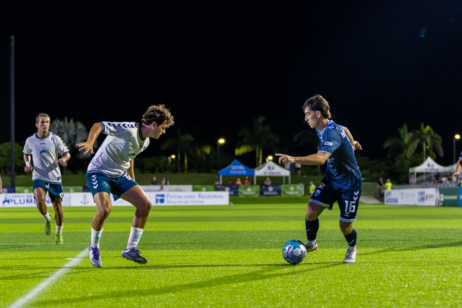 Jugadores de fútbol en partido nocturno Jugadores de fútbol en partido nocturno