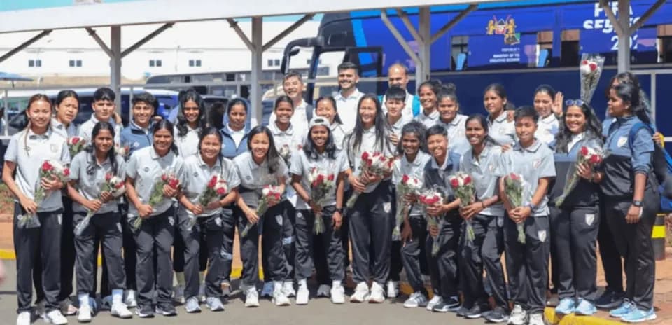 Equipo femenino posando con flores en el aeropuerto Equipo femenino posando con flores en el aeropuerto