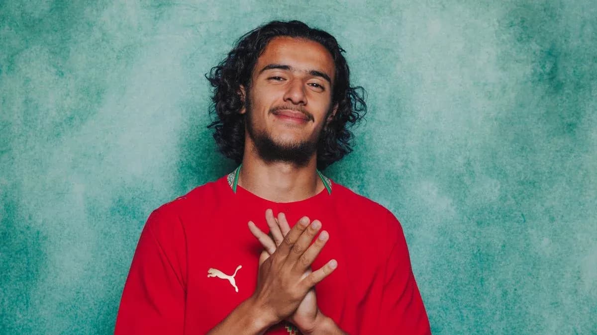 Jugador con camiseta roja sonriendo frente a fondo verde Jugador con camiseta roja sonriendo frente a fondo verde