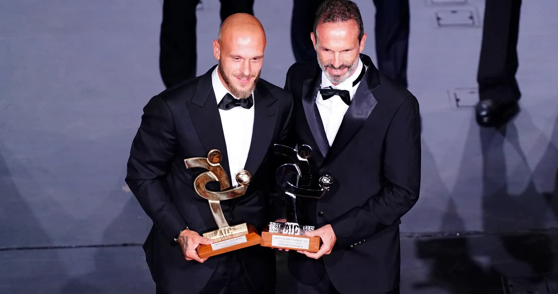 Dos hombres con trofeos en ceremonia de premiación Dos hombres con trofeos en ceremonia de premiación