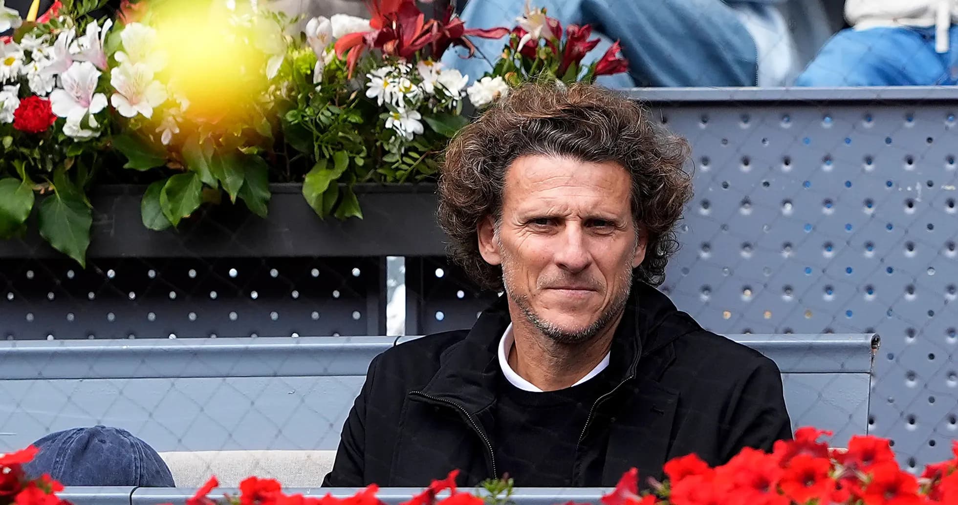 Hombre sentado en un palco rodeado de flores Hombre sentado en un palco rodeado de flores